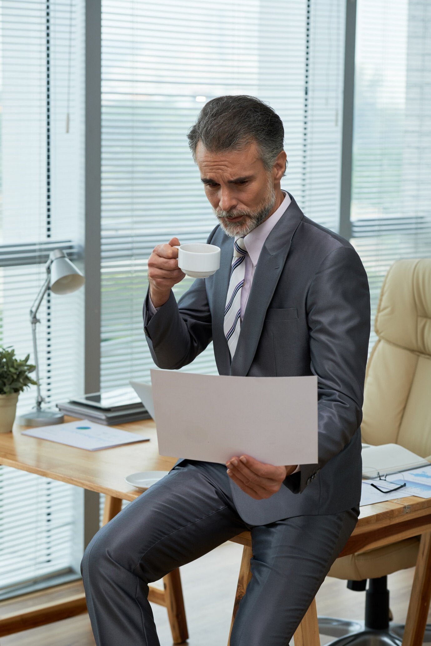 portrait-powerful-ceo-perching-desk-browsing-throught-report-sipping-coffee_1098-19223.jpg